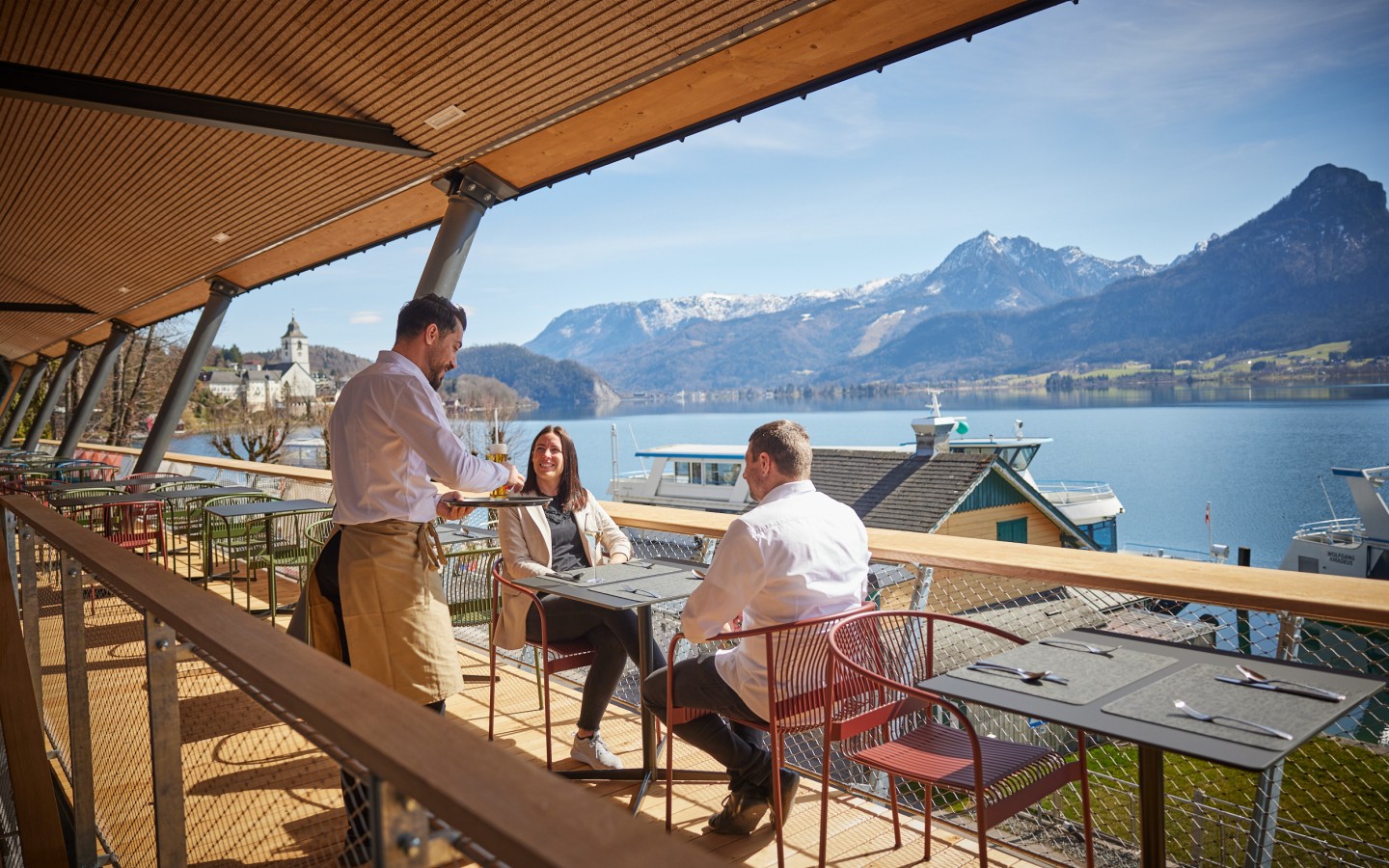 Kellner und Gäste auf der Seeterrasse des Café & Restaurant EQ mit Blick auf den Wolfgangsee 