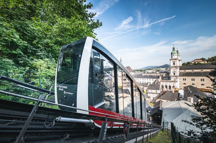 FestungsBahn fährt auf den Festungsberg mit Blick auf St. Peter Stiftskirche und Altstadt.