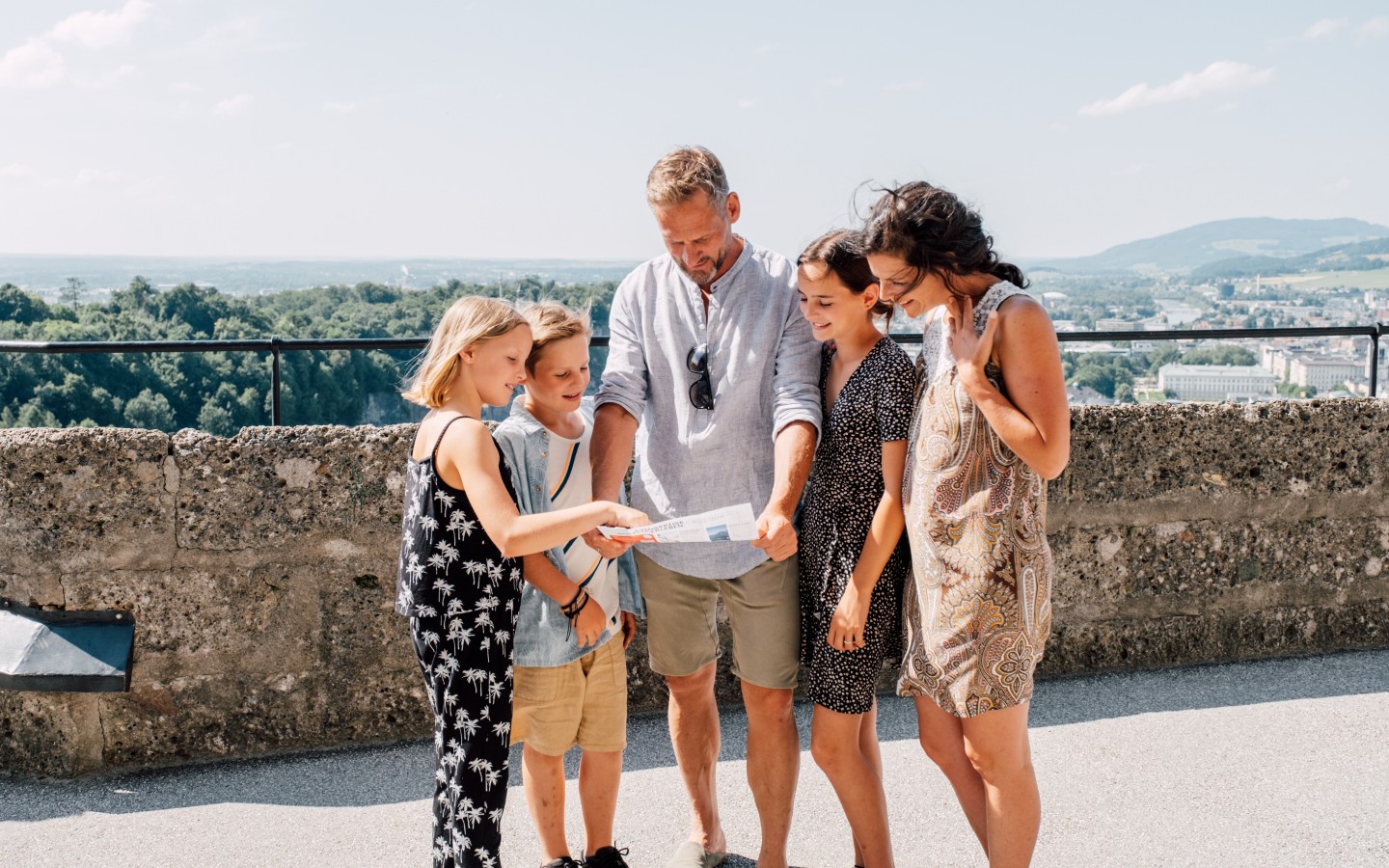 Familie mit drei Kindern sieht auf einen Plan auf dem Mönchsberg in Salzburg