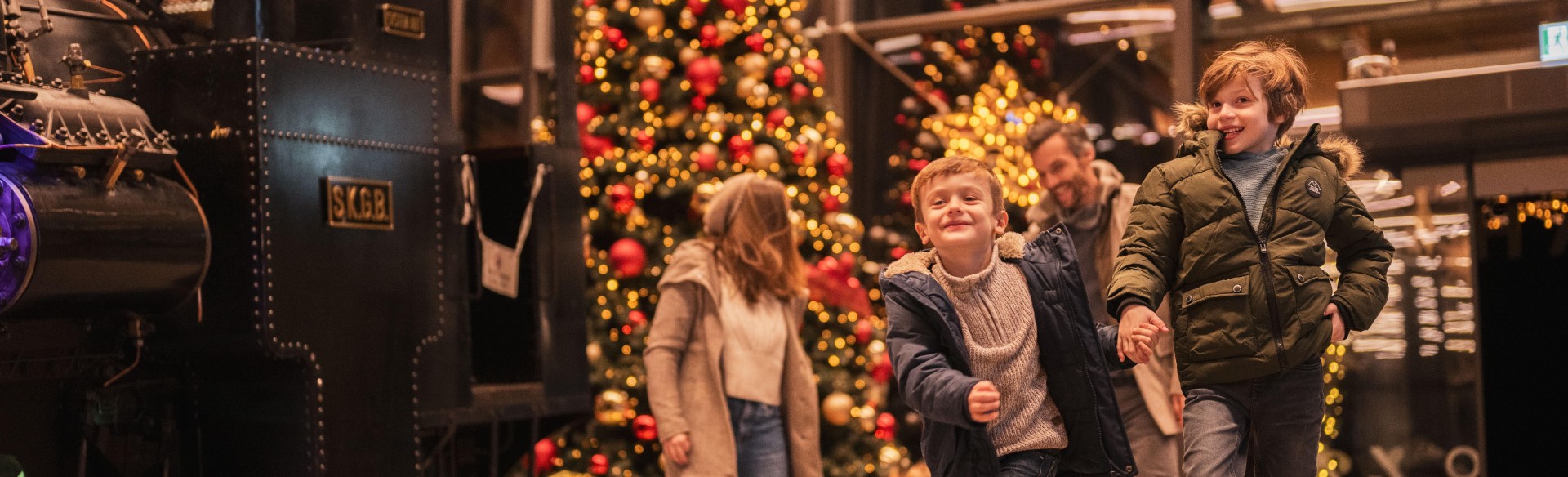 Weihnachtlich geschmücktes ErlebnisQuartier durch die hohen Fenster sieht man im inneren des Gebäudes einen deckenhohen geschmückten Weihnachtsbaum. 