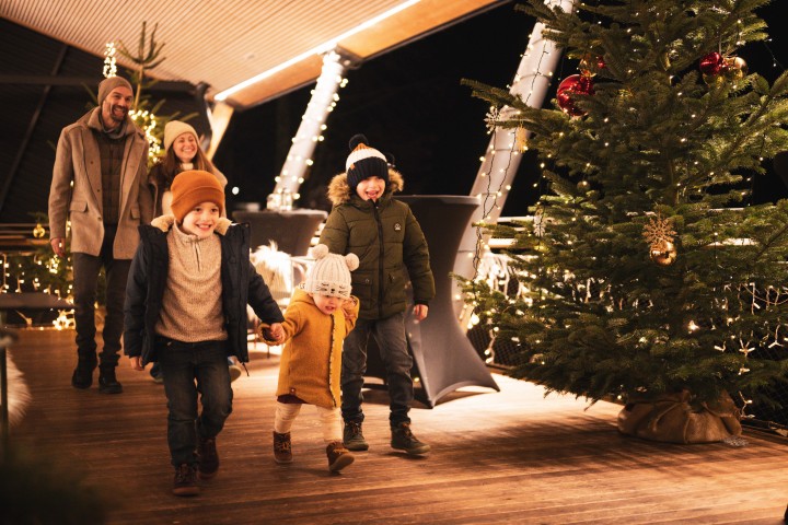 Familie auf der Terrasse des ErlebnisQuartiers die weihnachtlich geschmückt ist 