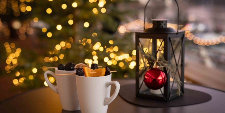 Zwei Personen stoßen mit Weingläsern auf der Seeterrasse des Café & Restaurant EQ an. Im Hintergrund sind man den Wolfgangsee und eine beeindruckende Berglandschaft im Sommer 