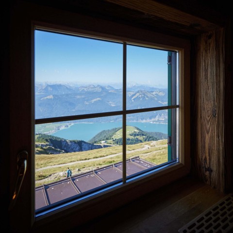 Blick aus einem Fenster ins Tal wo man den Wolfgangsee sieht.