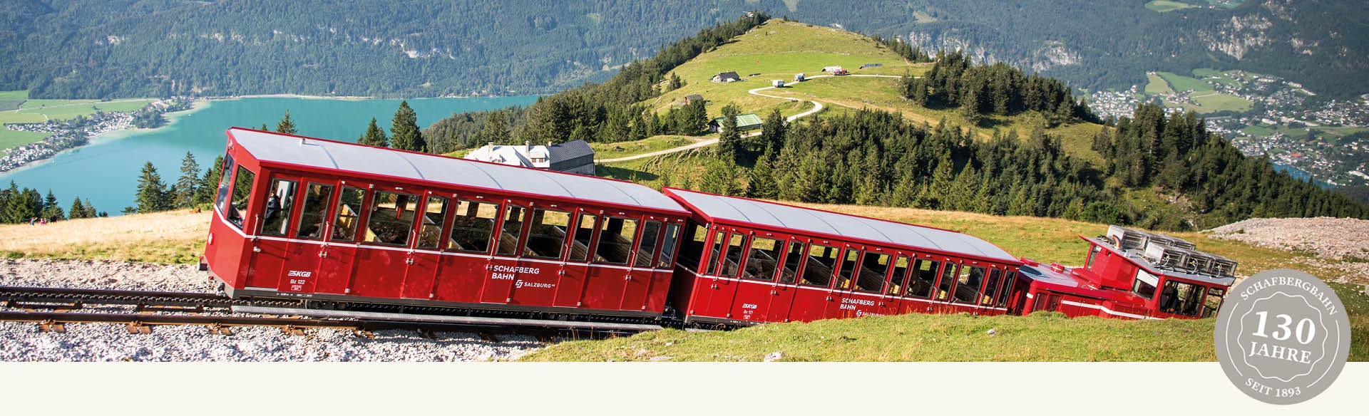 SchafbergBahn auf dem Weg zu Gipfel im Hintergrund sieht man die Schafbergalm und den blauen Wolfgangsee an einem Sommertag